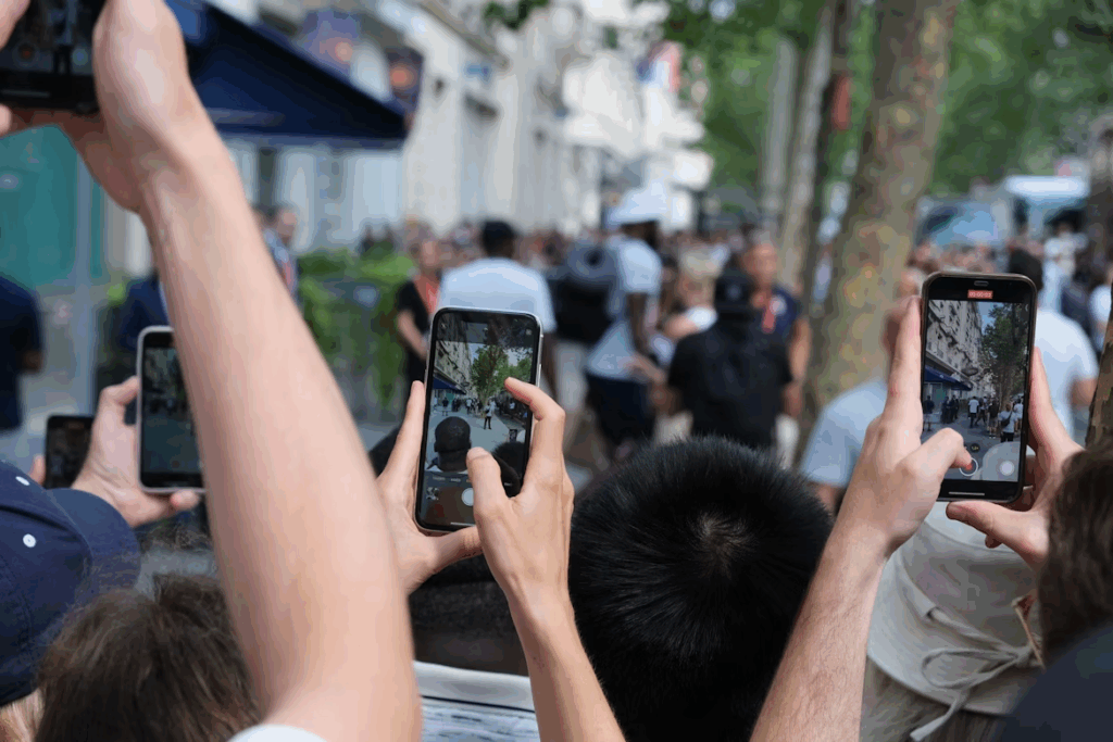 People in a crowd use smartphones to record a street protest, showing how social media captures social movements.