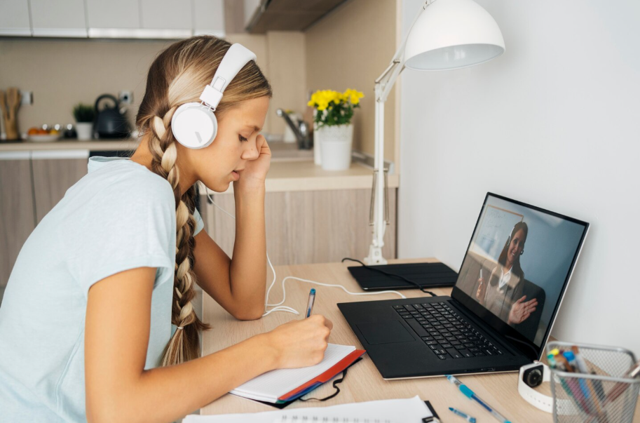 Teen girl with headphones watching an online lesson on her laptop, representing remote learning.