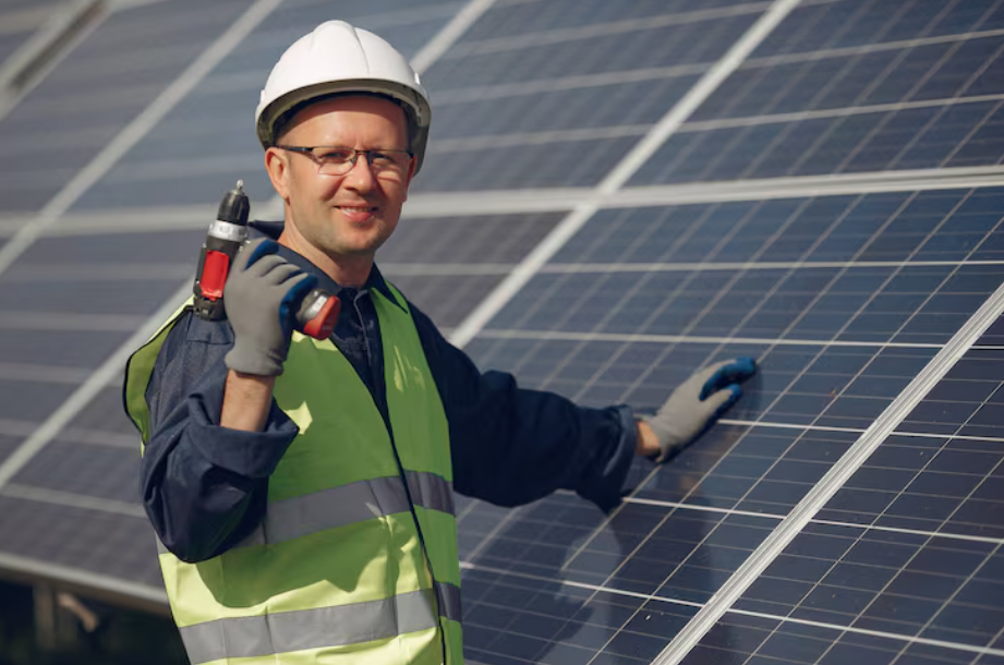 Solar technician in safety gear installing panels, representing the growth of global renewable energy jobs.