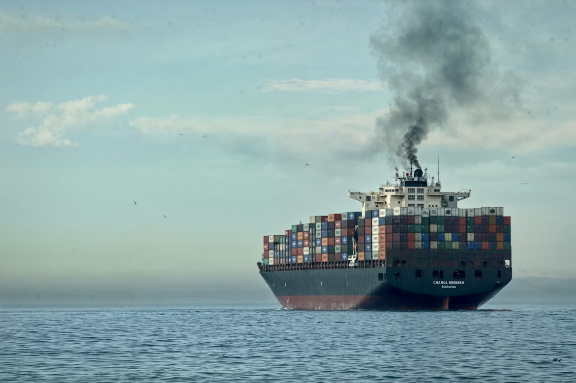 Large container ship emitting dark exhaust over the ocean, highlighting air pollution from global shipping.