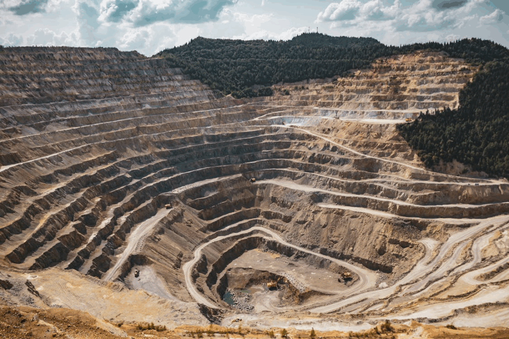 Aerial view of a large open-pit mine carved into terraced layers, illustrating rare earth mineral extraction.