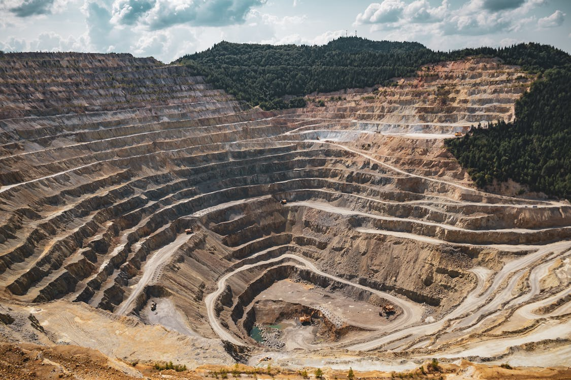 Aerial view of a large open-pit mine carved into terraced layers, illustrating rare earth mineral extraction.
