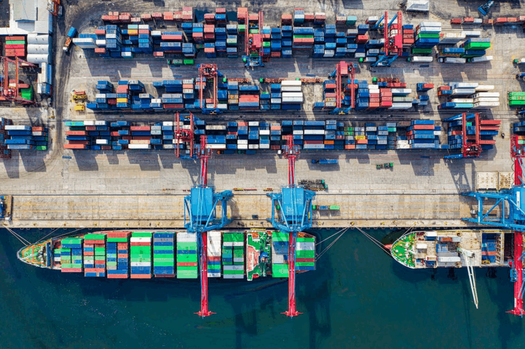 Aerial view of a busy container port with cargo ships and cranes, illustrating global trade projects.