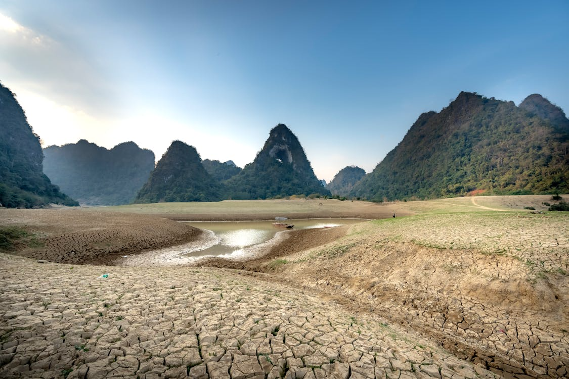 Cracked dry lakebed surrounded by green mountains, showing the growing impact of global water scarcity.