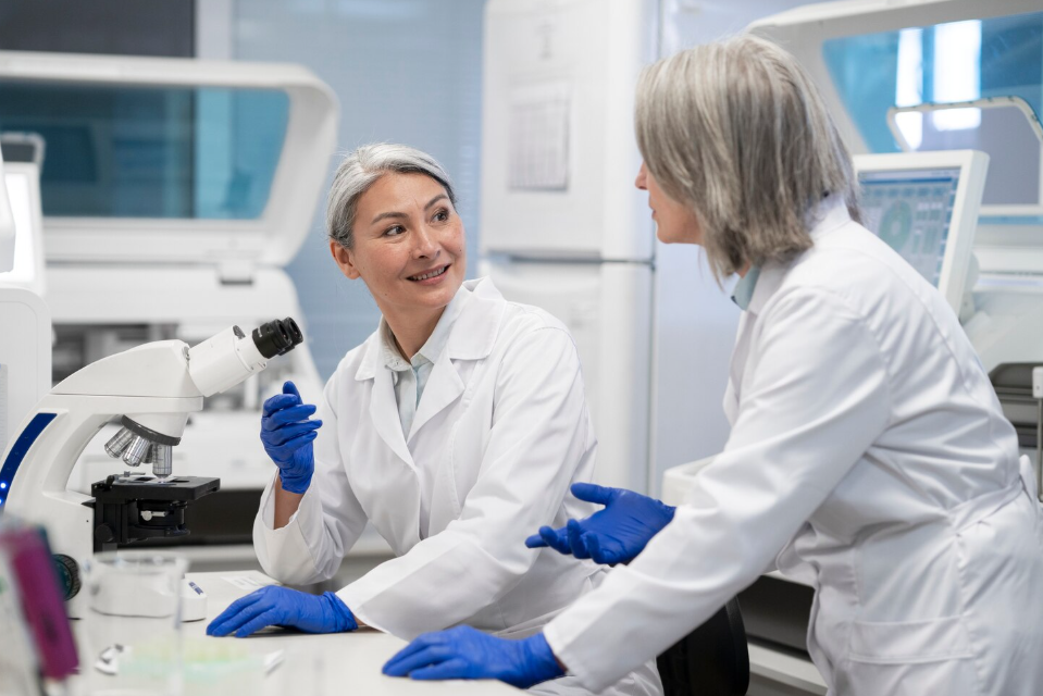 Two women scientists in lab coats discussing research, highlighting women in global innovation and scientific leadership.