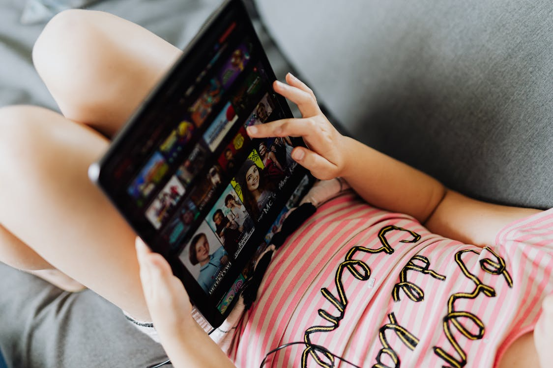 Person browsing a streaming platform on a tablet, showing how global streaming services shape viewing habits.