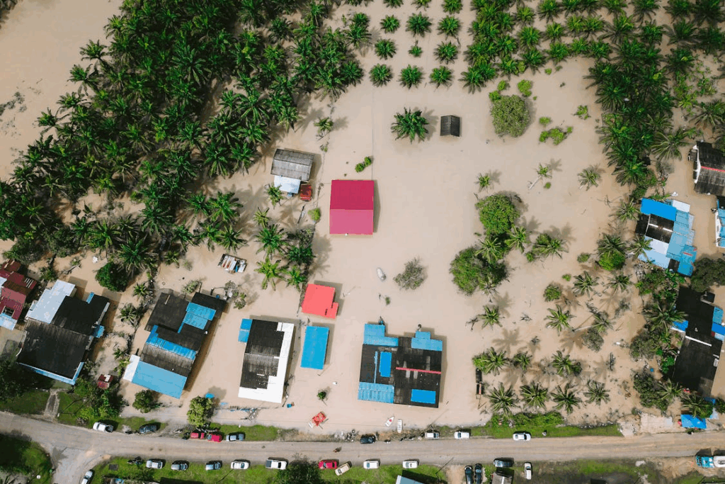 Aerial view of homes and palm trees surrounded by floodwater, showing how extreme weather drive climate migration.